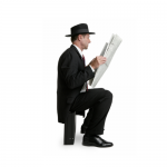 man in a hat reading a newspaper sitting on a briefcase